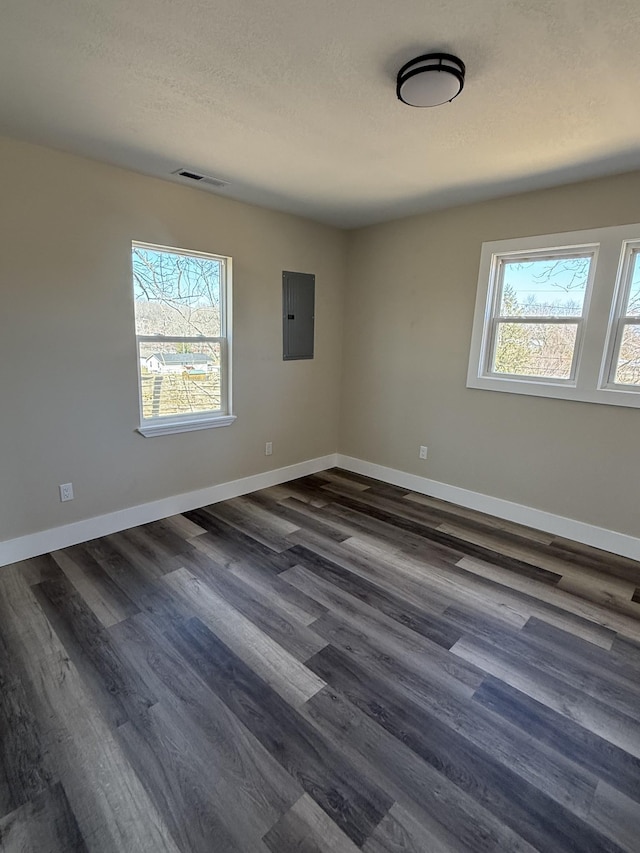 unfurnished room with baseboards, dark wood-type flooring, and a healthy amount of sunlight