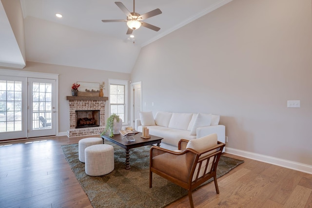 living area featuring a brick fireplace, a ceiling fan, baseboards, and light wood finished floors