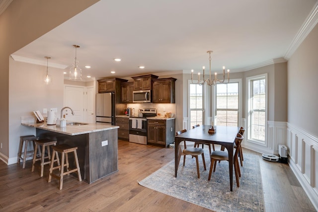 dining area featuring wood finished floors, recessed lighting, wainscoting, crown molding, and a chandelier