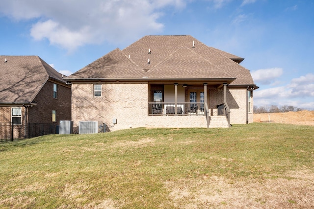 back of property with a yard, brick siding, roof with shingles, and a patio area