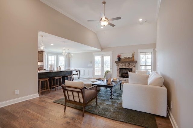 living room with plenty of natural light, a brick fireplace, and wood finished floors