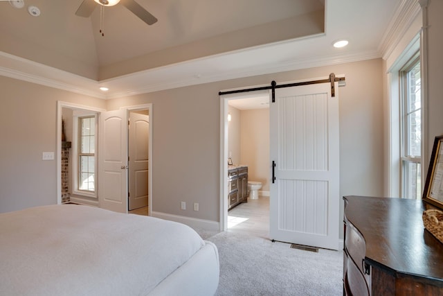 bedroom with a barn door, light carpet, a raised ceiling, and ensuite bath