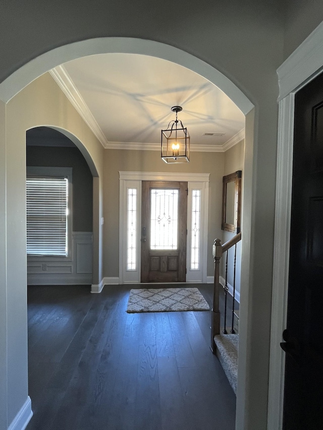 entrance foyer with dark wood-style floors, stairway, wainscoting, and crown molding