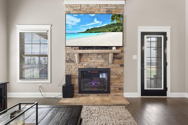 living area featuring a fireplace, baseboards, and wood finished floors