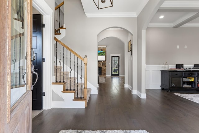 foyer featuring arched walkways, wood finished floors, stairs, and ornamental molding