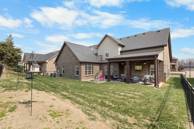 rear view of house with a yard, a patio, brick siding, and a fenced backyard