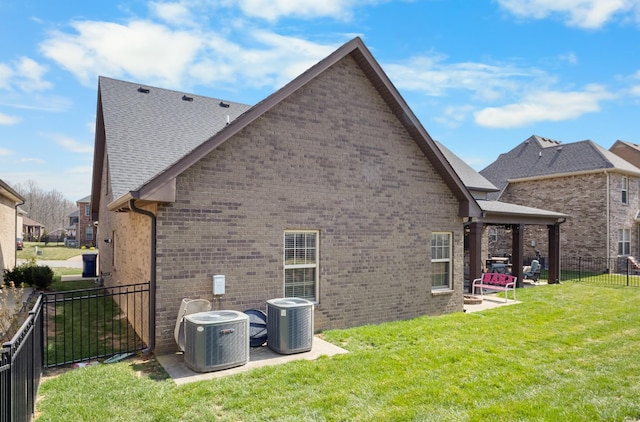 rear view of house featuring a yard, a patio, brick siding, and central AC unit