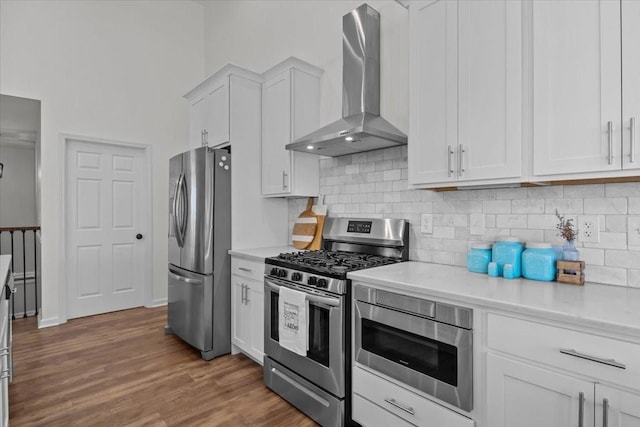 kitchen with white cabinets, stainless steel appliances, light countertops, and wall chimney range hood