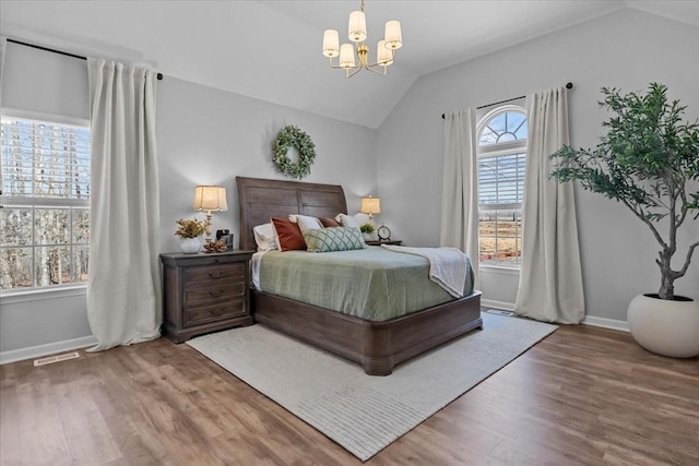 bedroom featuring lofted ceiling, a notable chandelier, wood finished floors, and visible vents