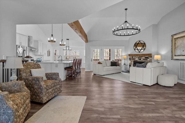 living area featuring high vaulted ceiling, an inviting chandelier, dark wood-style floors, and a fireplace