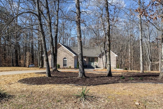 view of front of house featuring a view of trees and brick siding