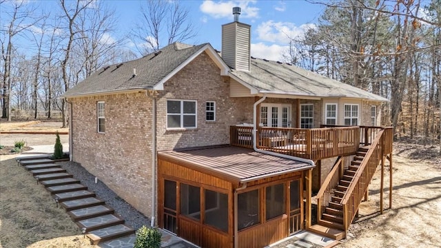 back of property featuring stairway, brick siding, a chimney, and a sunroom