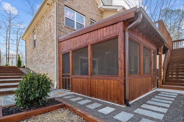 view of property exterior featuring brick siding and a sunroom