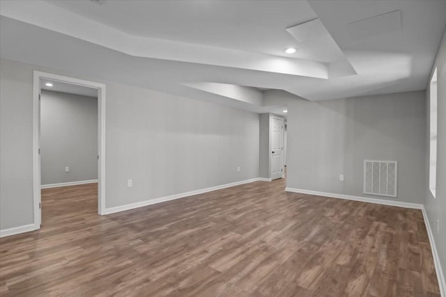 unfurnished room with visible vents, baseboards, a tray ceiling, recessed lighting, and wood finished floors