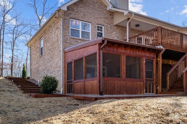 back of house with brick siding, stairway, a chimney, and a sunroom