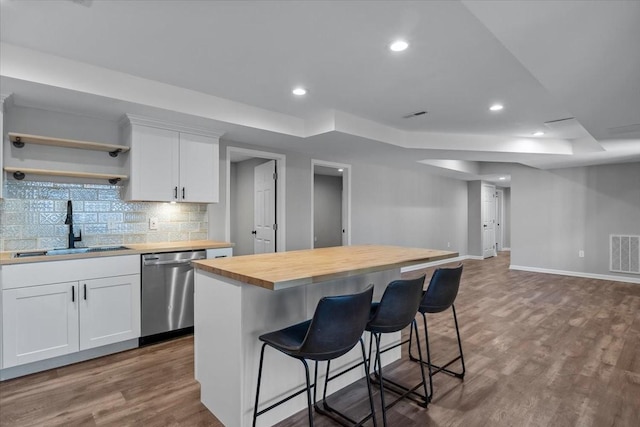 kitchen with visible vents, a sink, dark wood-type flooring, stainless steel dishwasher, and butcher block counters