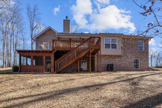 back of house with a wooden deck, a sunroom, a chimney, stairs, and brick siding