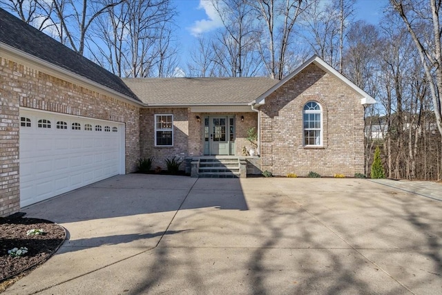 ranch-style home with french doors, concrete driveway, an attached garage, a shingled roof, and brick siding