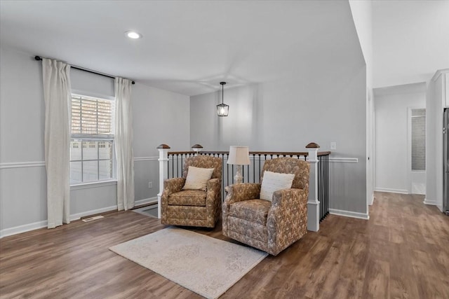 living area with baseboards, an upstairs landing, visible vents, and wood finished floors