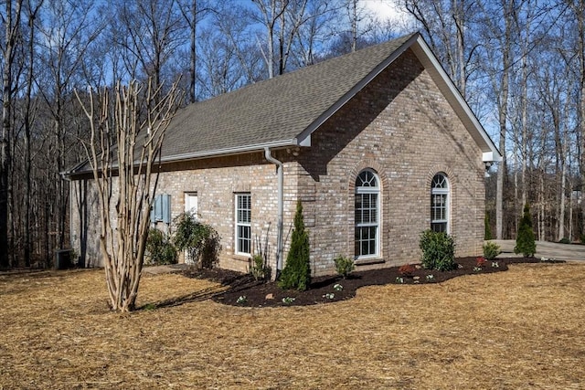 view of side of property featuring brick siding and roof with shingles