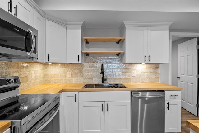 kitchen with a sink, white cabinets, butcher block countertops, and stainless steel appliances