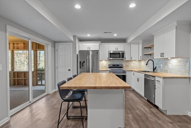 kitchen with visible vents, butcher block countertops, a sink, open shelves, and stainless steel appliances