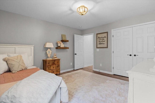 bedroom featuring wood finished floors, baseboards, and a closet