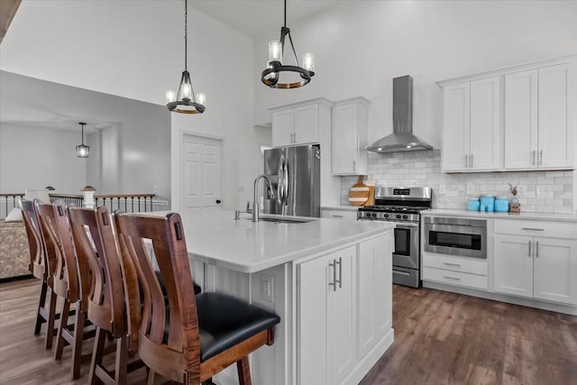 kitchen featuring light countertops, appliances with stainless steel finishes, dark wood-style flooring, and wall chimney range hood