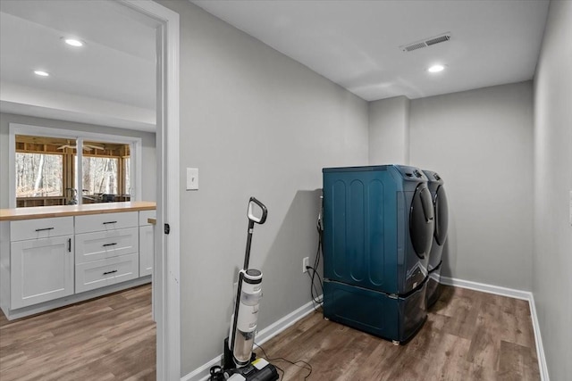 washroom with wood finished floors, visible vents, baseboards, laundry area, and washer and dryer