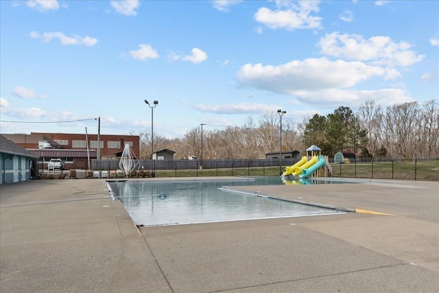 pool featuring playground community, a water slide, and fence