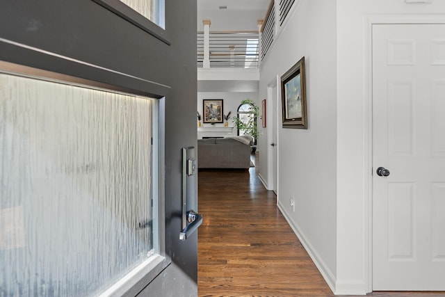 hallway with a towering ceiling, baseboards, and wood finished floors