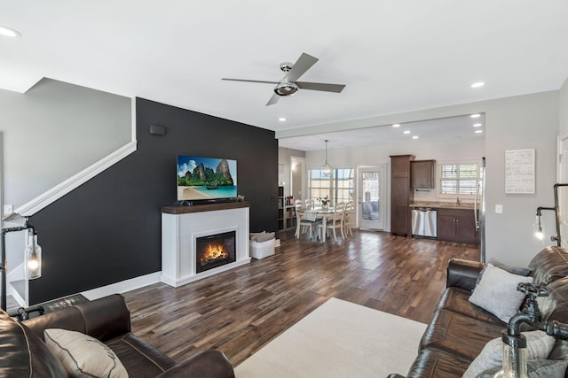 living room featuring a glass covered fireplace, recessed lighting, dark wood-style floors, and ceiling fan