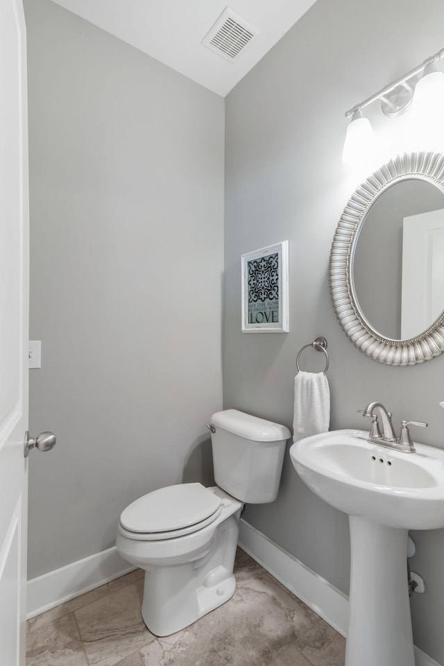 half bath featuring visible vents, baseboards, and toilet