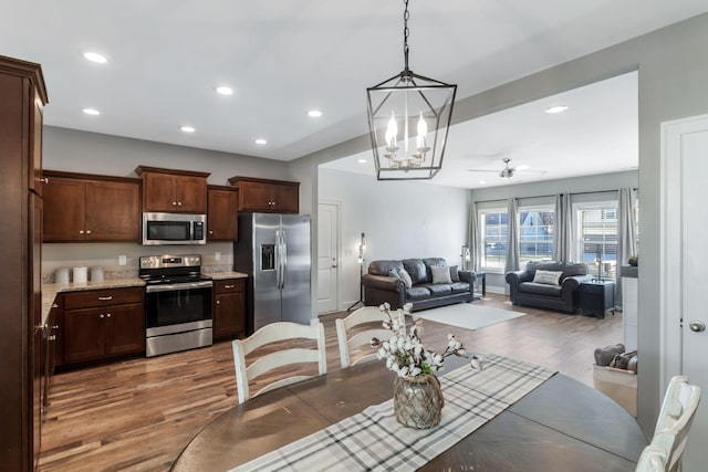 dining room featuring recessed lighting, ceiling fan with notable chandelier, and wood finished floors