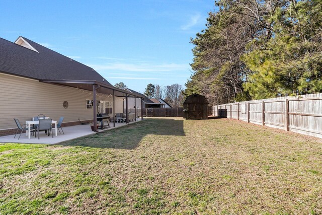 view of yard featuring a patio area, a storage unit, an outbuilding, and a fenced backyard