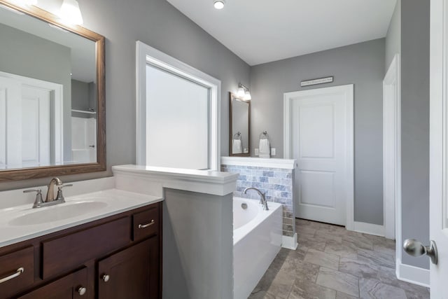 full bathroom with baseboards, a bath, and vanity