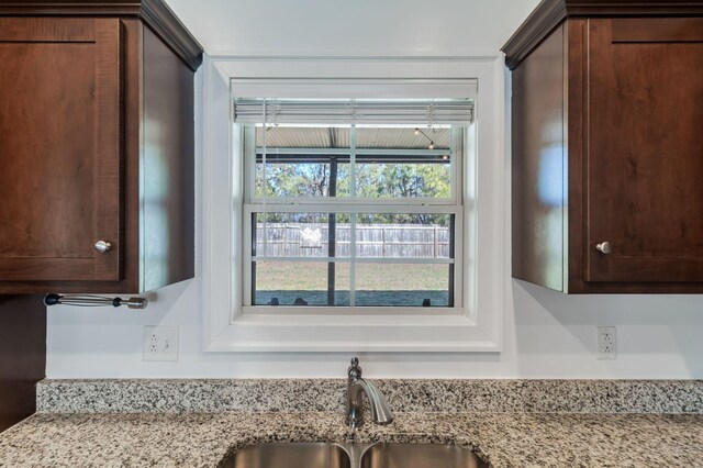 interior details with light stone counters, dark brown cabinets, and a sink