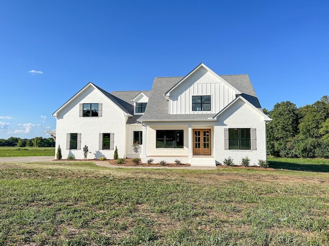 modern inspired farmhouse with board and batten siding, a front lawn, and a shingled roof