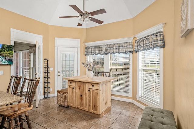 kitchen featuring ceiling fan, baseboards, light brown cabinetry, butcher block countertops, and vaulted ceiling