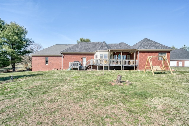 rear view of house with brick siding, a deck, and a lawn