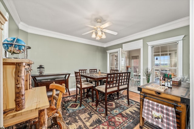 dining space featuring a ceiling fan, wood finished floors, baseboards, and ornamental molding