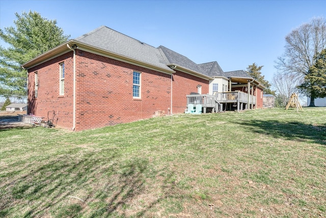 rear view of house featuring a wooden deck, a lawn, and brick siding