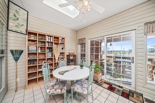 tiled dining space with wooden walls, visible vents, and ceiling fan