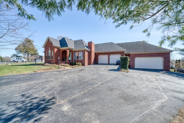 view of front of home featuring roof with shingles, an attached garage, a chimney, aphalt driveway, and brick siding