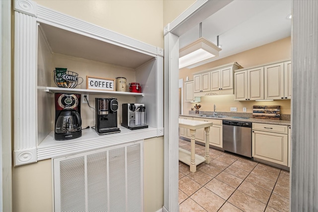 kitchen with light tile patterned floors, a sink, light countertops, cream cabinetry, and stainless steel dishwasher