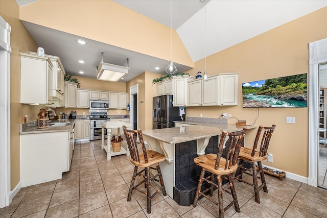 kitchen featuring recessed lighting, a sink, vaulted ceiling, appliances with stainless steel finishes, and a kitchen breakfast bar