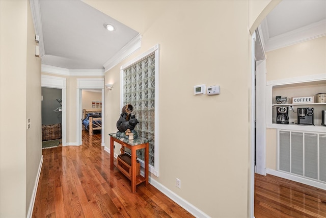 corridor featuring visible vents, wood finished floors, baseboards, and ornamental molding