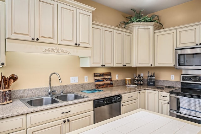 kitchen with cream cabinets, stainless steel appliances, light countertops, and a sink