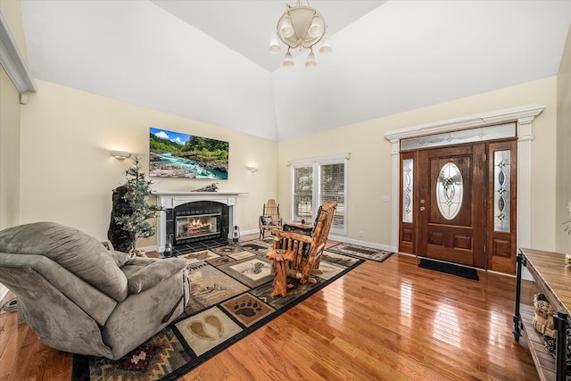 entryway with baseboards, wood-type flooring, a tile fireplace, and vaulted ceiling