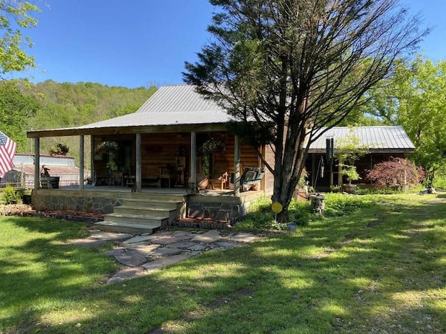 rear view of property with a porch, metal roof, and a yard